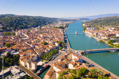 General view of Vienne city on banks of Rhone river surrounded by high hills in sunny summer day, Isere, France © JackF