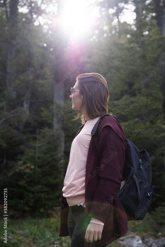 Woman hiker at mountain forest shined by the sun at sunset Woman hiker at mountain forest shined by the sun at sunset