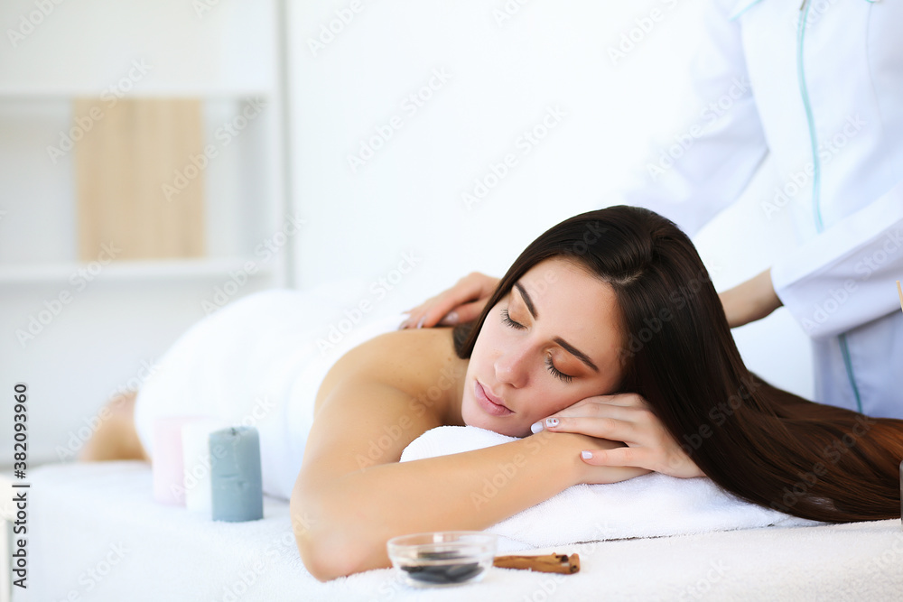Beautiful brunette girl lying with eyes closed on the front of the body while a masseur massages her back Beautiful brunette girl lying with eyes closed on the front of the body while a masseur massages her back