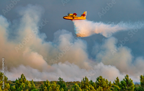 Profile view of hydroplane dumping water over huge fire photo