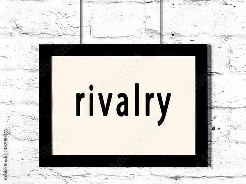 Black frame hanging on white brick wall with inscription rivalry