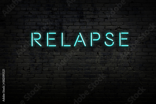 Neon sign. Word relapse against brick wall. Night view photo