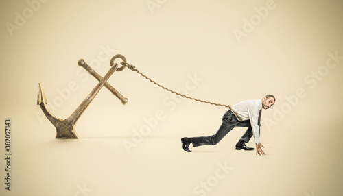 businessman in starting position tied to a big anchor photo