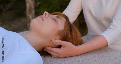 Woman do traditional chinese massage gua sha outdoors in summer garden