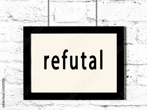 Black frame hanging on white brick wall with inscription refutal