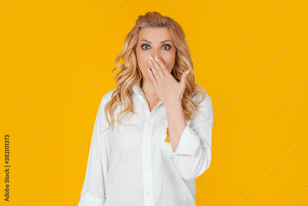 Blandin european middle-aged woman in white shirt, panic in shock upset, frowning, covering her mouth with her hand, disappointed to hear bad news unhappy standing on a yellow background Blandin european middle-aged woman in white shirt, panic in shock upset, frowning, covering her mouth with her hand, disappointed to hear bad news unhappy standing on a yellow background