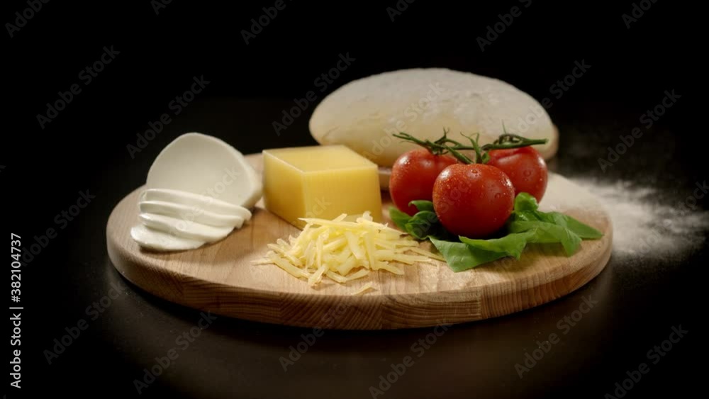 Italian pizza Margherita ingredients lie on a wooden board and ready to cook. The camera is
circling around. Dark background. Isolated Italian pizza Margherita ingredients lie on a wooden board and ready to cook. The camera is
circling around. Dark background. Isolated