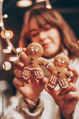 selective focus, noise effect: Merry Christmas and Happy New Year! Christmas cookies, gingerbread man figure holding a smiling woman in her hands