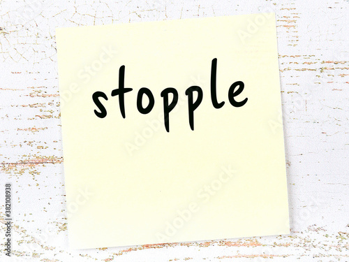 Fotografie Yellow sticky note on wooden wall with handwritten word stopple