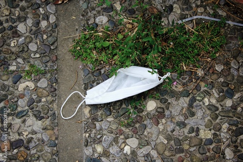 Surgical face mask thrown on the ground.