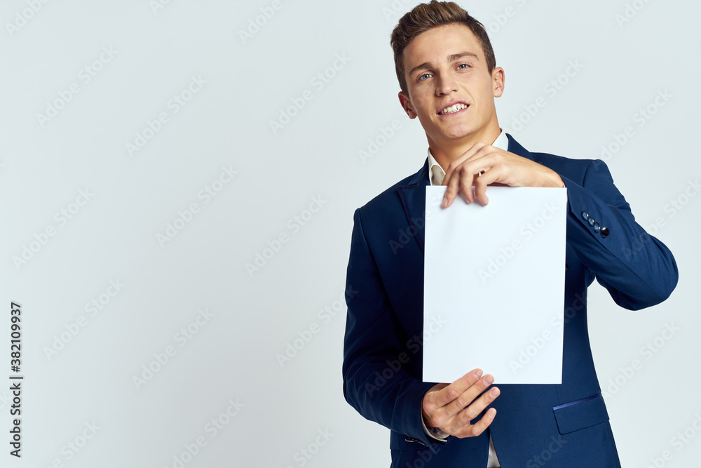 A business man in a suit holds a paper in the hand of an official manager light background A business man in a suit holds a paper in the hand of an official manager light background