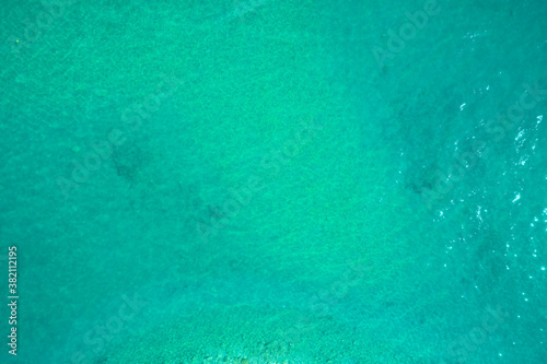 Turquoise water top view. Turquoise Water near to the Sand underneath forming many little waves reflecting the sun.