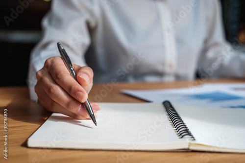Business people are using a pen to take notes, including calculators and financial reports on the desk. © PaeGAG