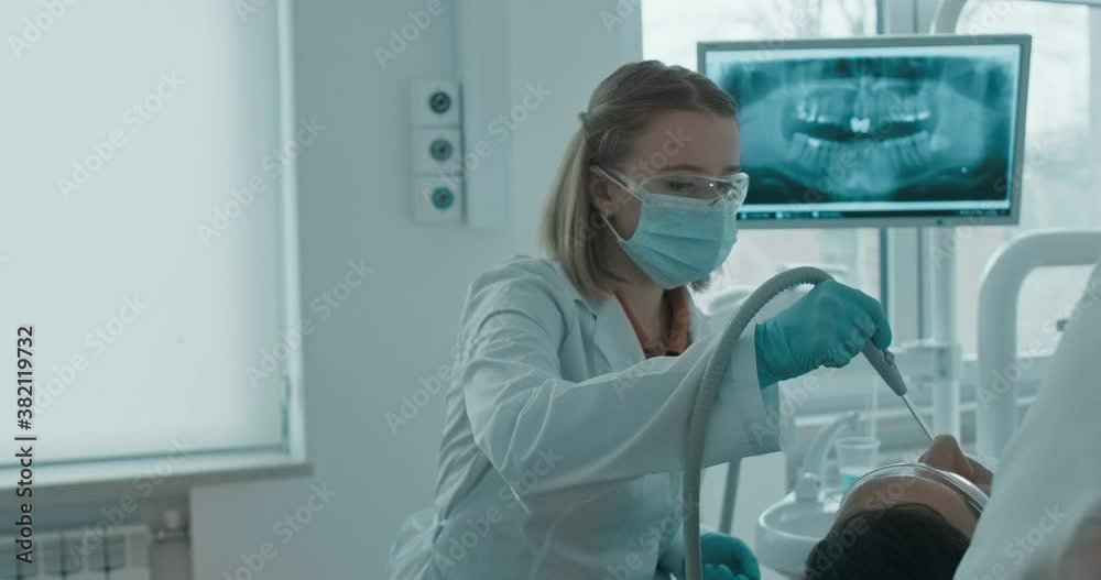 Nurse assisting the dentist and holding a saliva ejector Nurse assisting the dentist and holding a saliva ejector