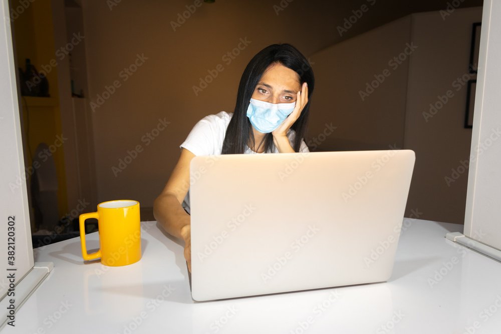 Front view of beaituful Caucasian woman with mask on sitting in front of laptop bored. Isolation during pandemic concept. Front view of beaituful Caucasian woman with mask on sitting in front of laptop bored. Isolation during pandemic concept.