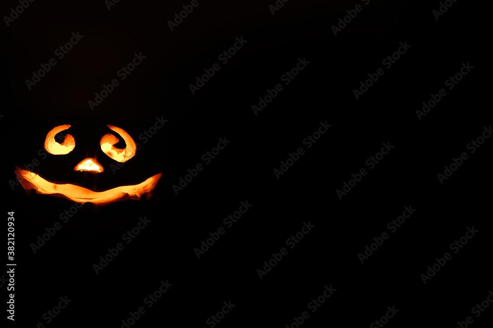 Fototapeta premium glowing smiling face Halloween pumpkin, candle holder, isolated on night dark black background. space for text