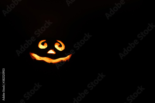 glowing smiling face Halloween pumpkin, candle holder, isolated on night dark black background. space for text
