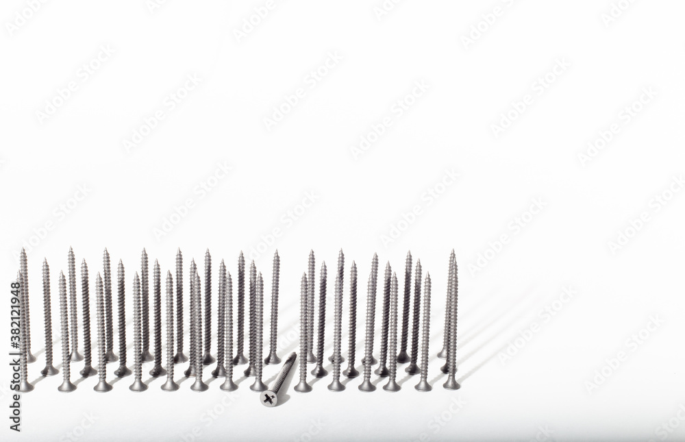 self-tapping screws in black are lined up in three rows on a white background. place for text. self-tapping screws in black are lined up in three rows on a white background. place for text.