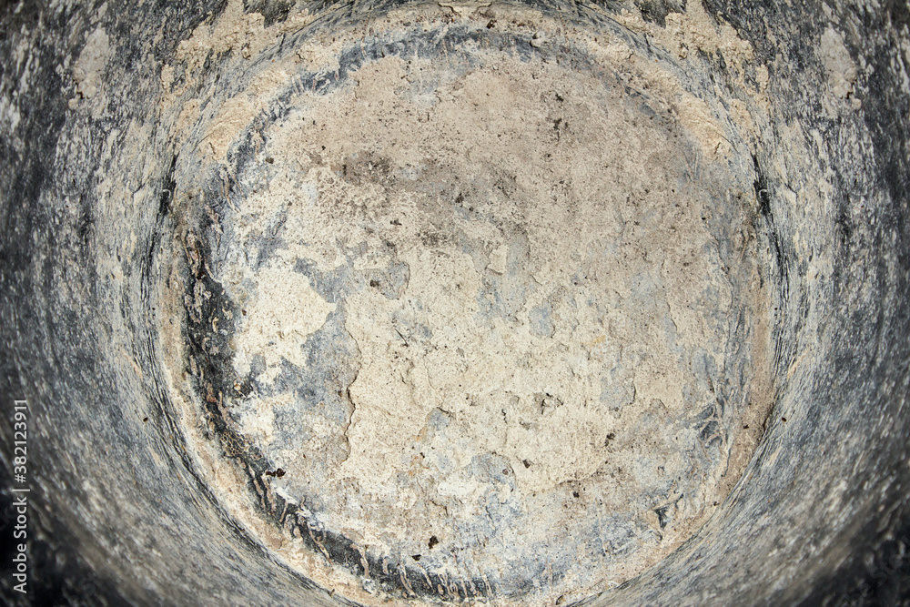 Abstract circular drawing made with dry and worn plaster and cement surrounded by dirt with white spots of paint. Texture background.