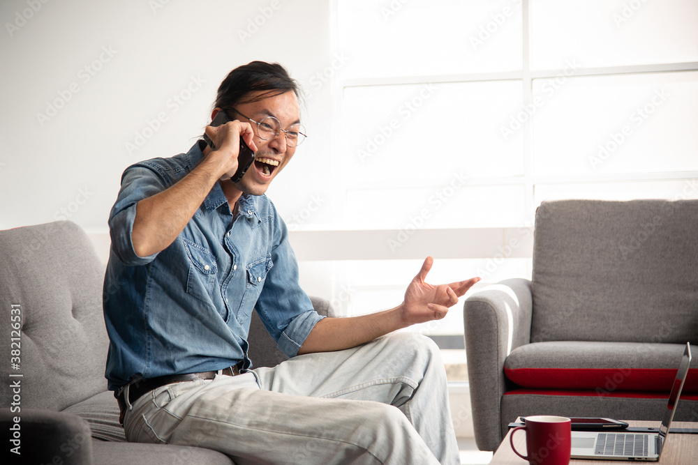 asian guy with eyewear happy screaming while talking on the phone asian guy with eyewear happy screaming while talking on the phone
