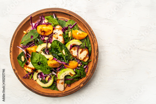 Healthy salad. Buddha bowl dish with chicken fillet, purple cabbage, avocado, spinach, tomatoes and nuts on a light background. Healthy balanced eating. space for text. top view