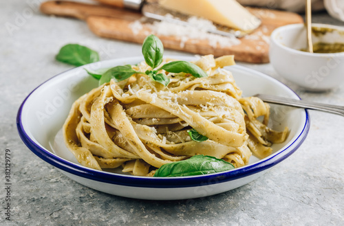 Tagliatelle pasta with pesto sauce and basil leafs.