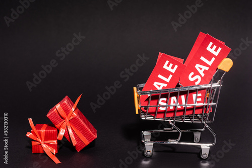 red gifts near toy cart with sale tags on dark background, black friday concept