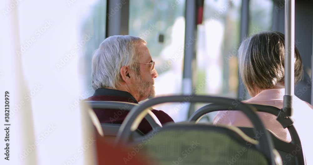 Senior couple talking together traveling inside bus