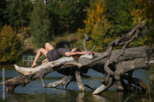 girl on an old tree in the lake