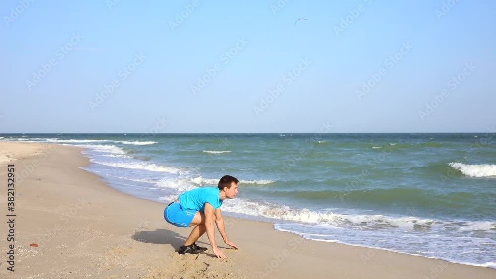 Young man doing burpees exercise at ocean beach working out in slow motion Young man doing burpees exercise at ocean beach working out in slow motion