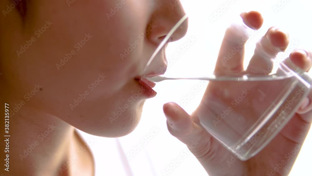 Close up shot of young woman taking pills with a glass of water. Healthcare and medicine concept. 4K