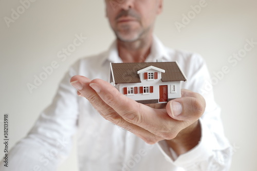petite maison dans la paume d'un homme en chemise blanche