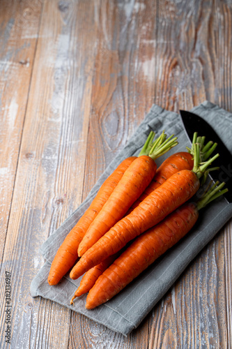 Ripe young carrots on light wooden background, top view for a shop magazine