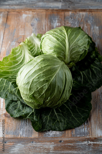 Two heads of young fresh green cabbage on rustic old wooden background, close up, top view