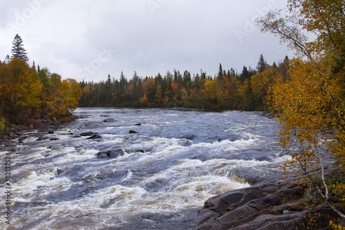 The Jacques-Cartier River seen flowing between wooded banks during a cloudy Fall afternoon, Shannon, Quebec, Canada photo