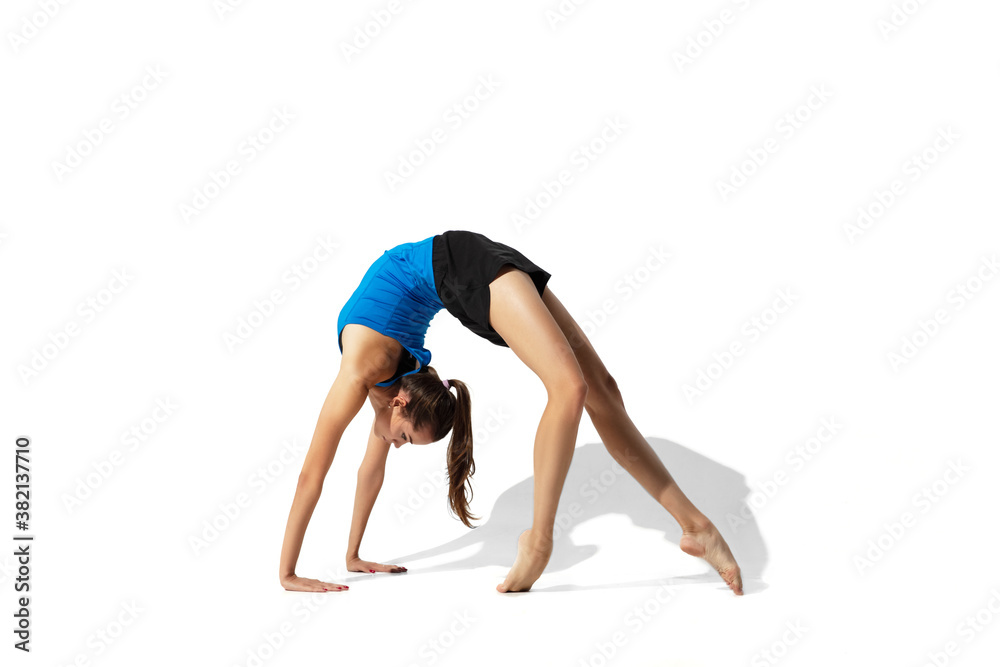 Split. Beautiful young female athlete stretching, training on white studio background, portrait with shadows. Sportive fit model in motion and action. Flexibility, healthy lifestyle, style concept.
