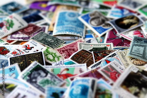 Blurred, defocused, tilt shift multicolored postage stamps collection from different countries closeup background with selective focus