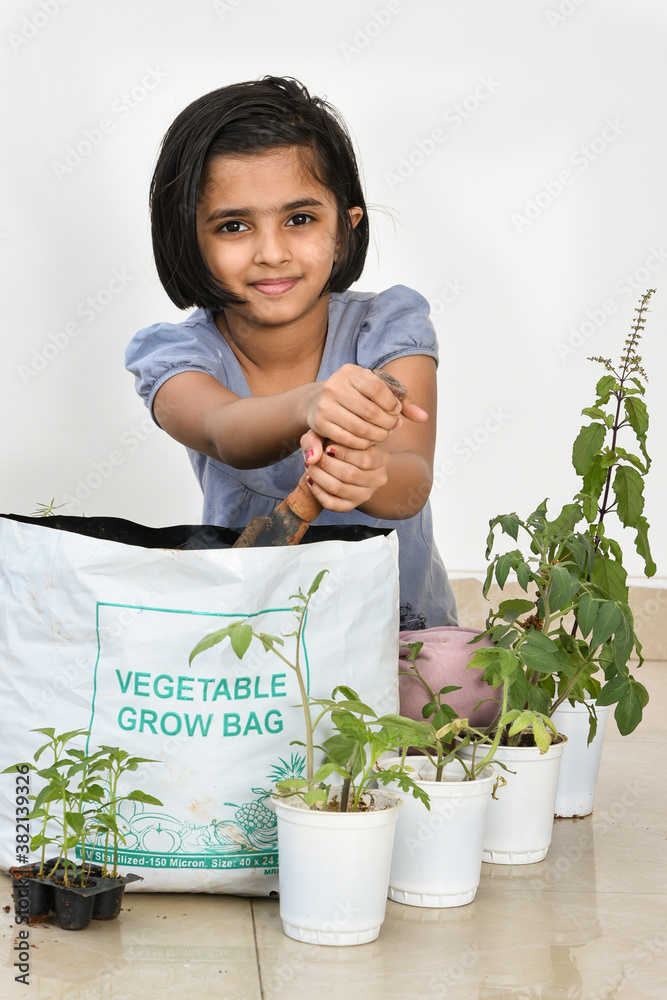 Cute young Indian girl kid in her organic vegetable garden. Cute Little