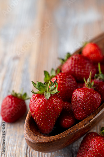 A whole wooden bowl of ripe seasonal strawberries  close up  side view  advertisement appetizing photo