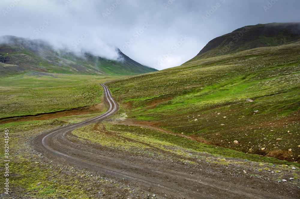 graveled road in the cloudy  green mountains on a rainy day in Island