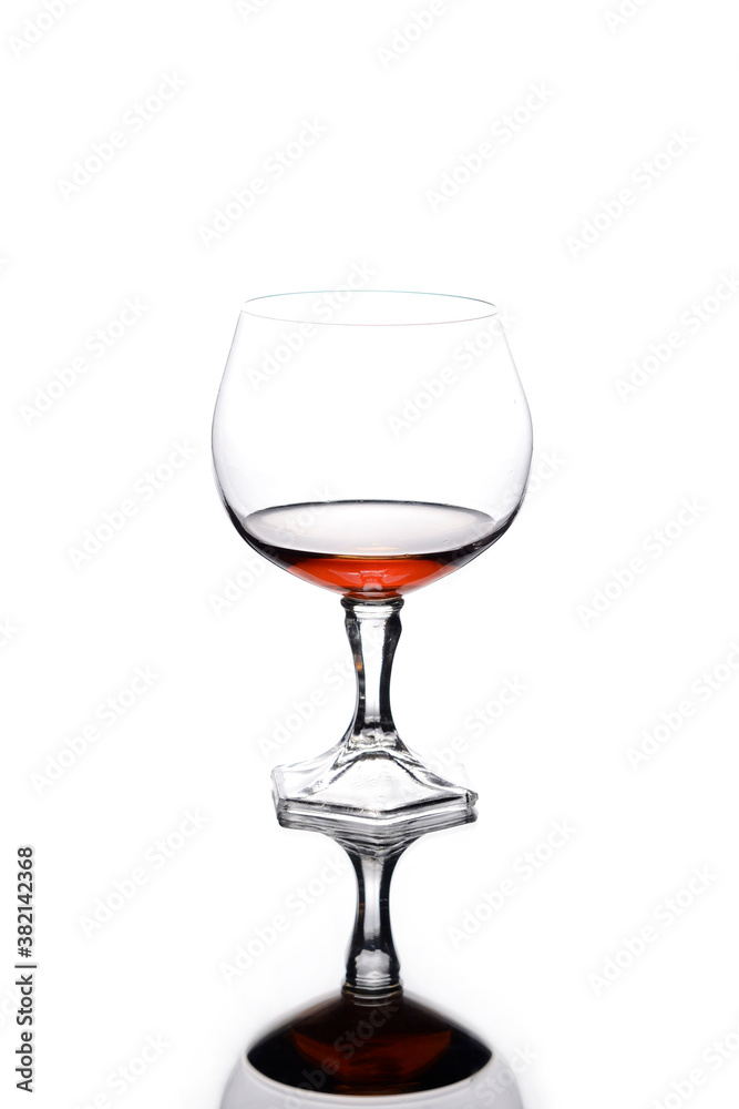 Glass of cognac with reflection on a white background.  Alcohol consumption.