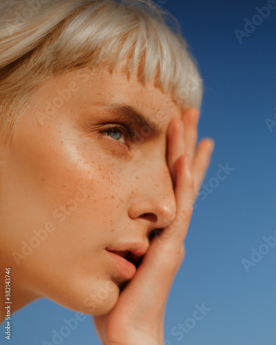 ?lose-up portrait of young blonde with blue eyes with freckles. Portrait of beautiful girl with natural makeup