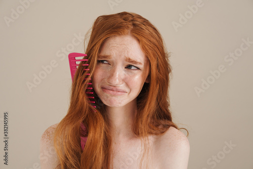 Valokuvatapetti Photo of redhead shirtless girl with comb in her hair crying on camera