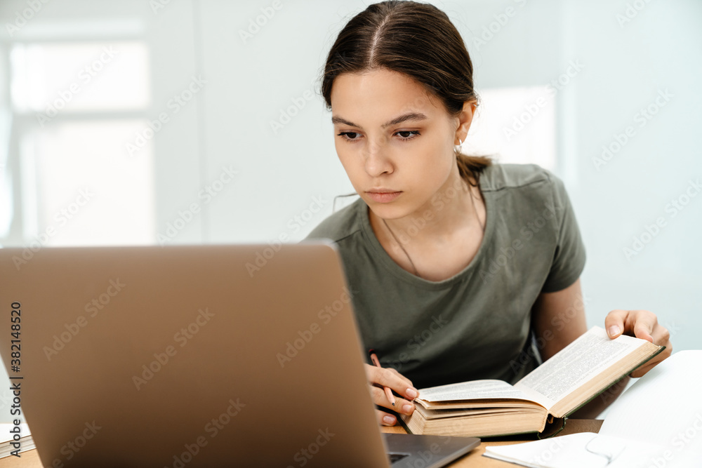 Image of focused student girl doing homework with laptop Image of focused student girl doing homework with laptop