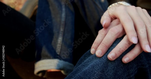 Close female hand caresses male hand leaned on knee