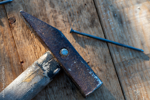 Old vintage hammer and nails on a wooden background, close-up, selective focus.