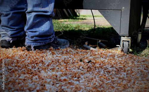 Wood shavings scattered on ground as man works lathe.