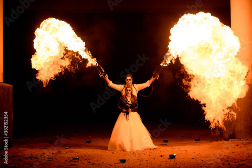 Halloween couple standing with flamethrower in hands. big fire photo