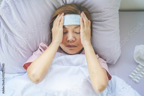 Obraz na płótnie Sick asian woman lying on bed have fever and using a cooling pad on head