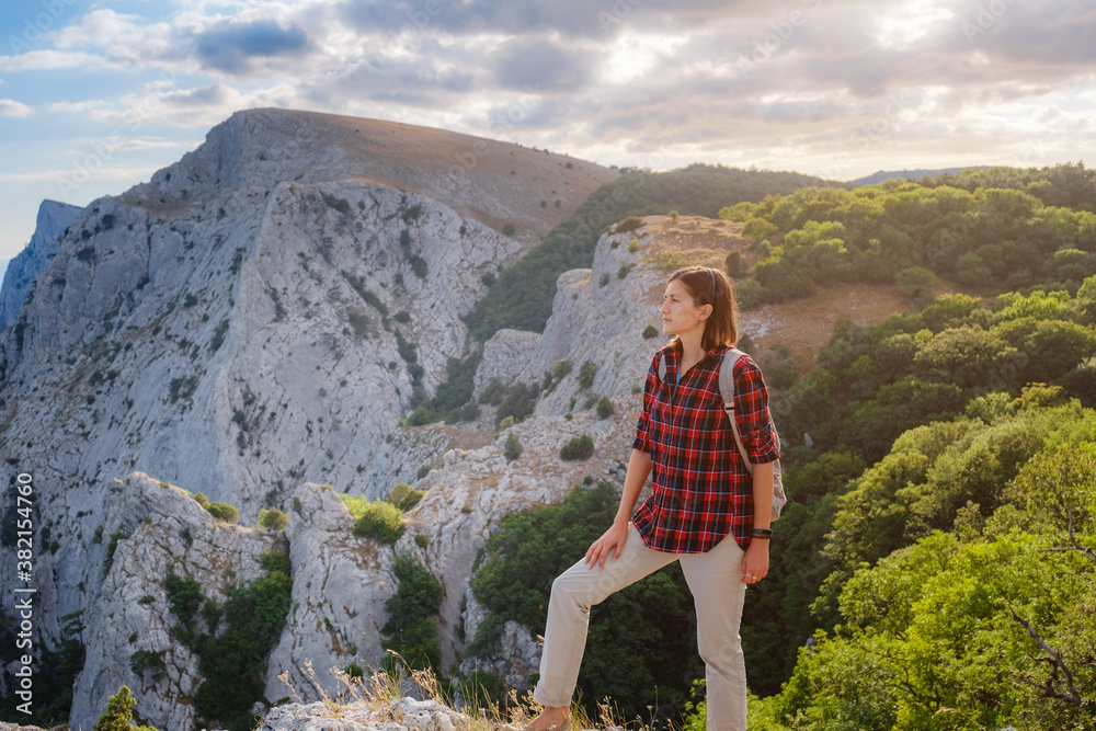 Naklejka premium Fit female hiker with backpack standing on a rocky mountain ridge